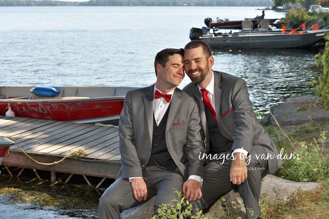 Two grooms snuggle on the dock after their Beachwood Resort wedding