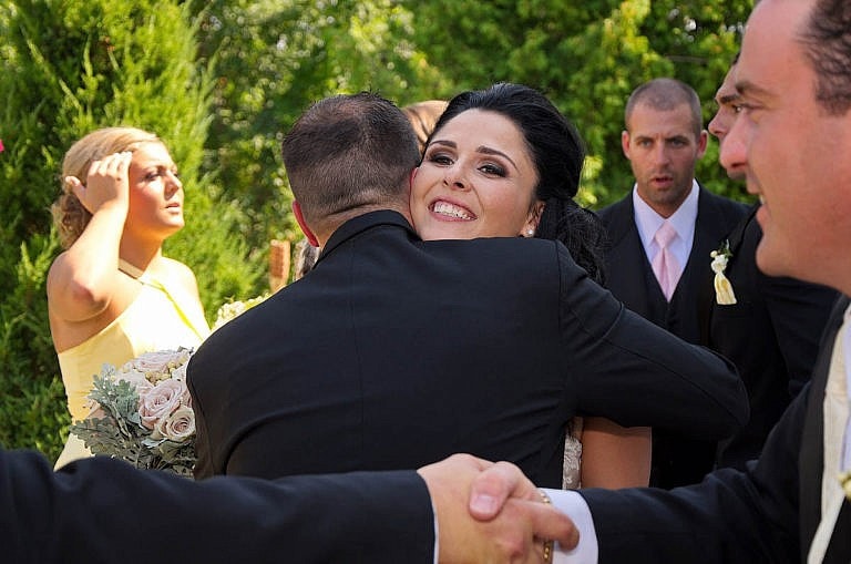 bride hugs groomsman after ceremony