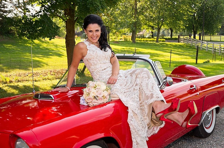 bride on hood of cherry red vintage thunderbird