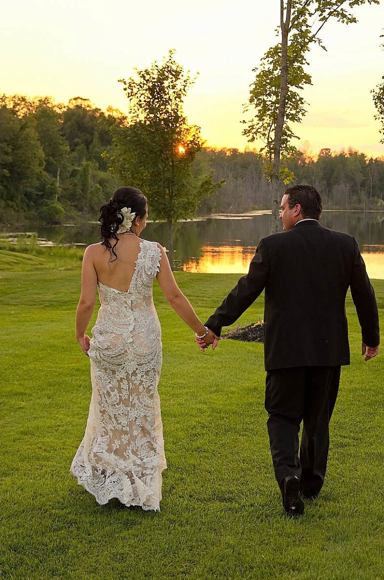 bride and groom stroll by pond at sunset at caledon wedding at Royal ambassador