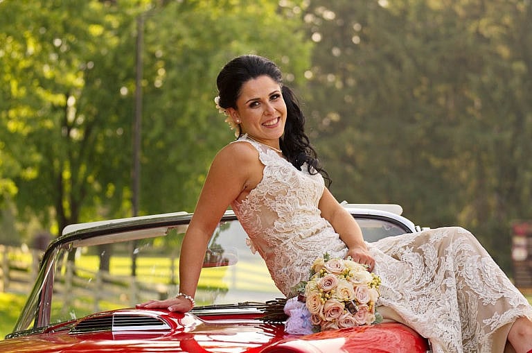 Bride on red vintage car at Caledon wedding at Royal Ambassador