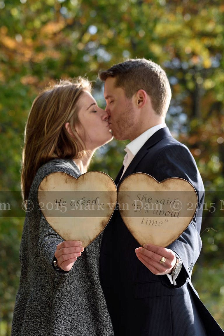 Orillia photographer, couple holds up wedding date sign made from two wooden hearts, save the date