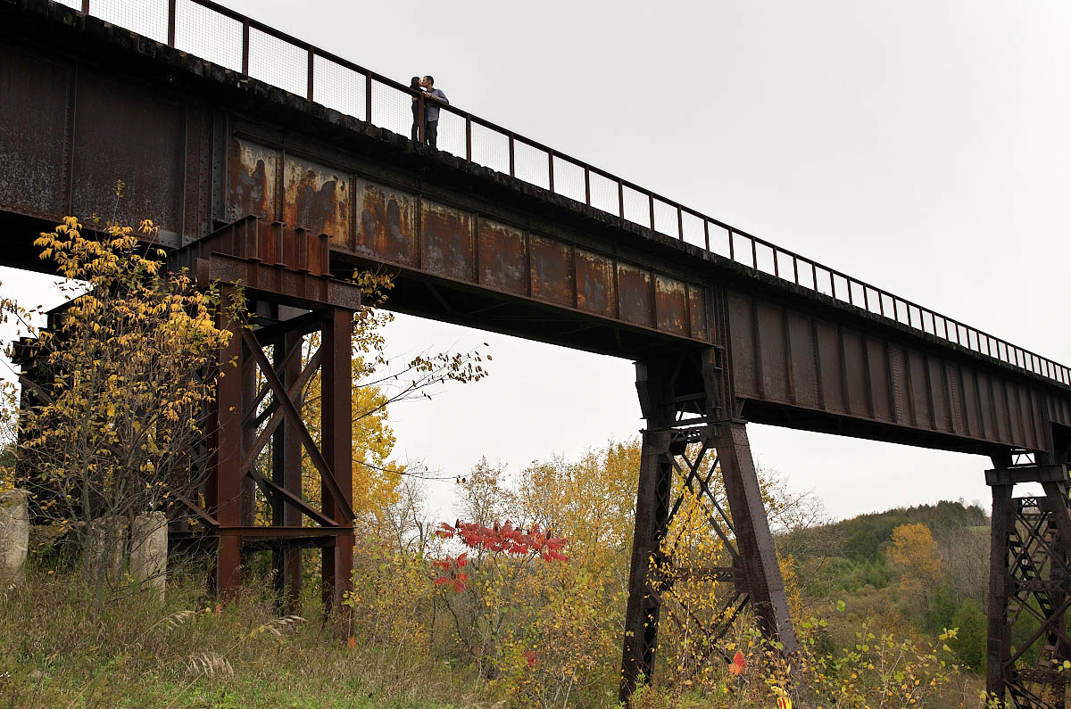 Young couple on Orange Corners Trestle Bridge during Omemee engagement photography session