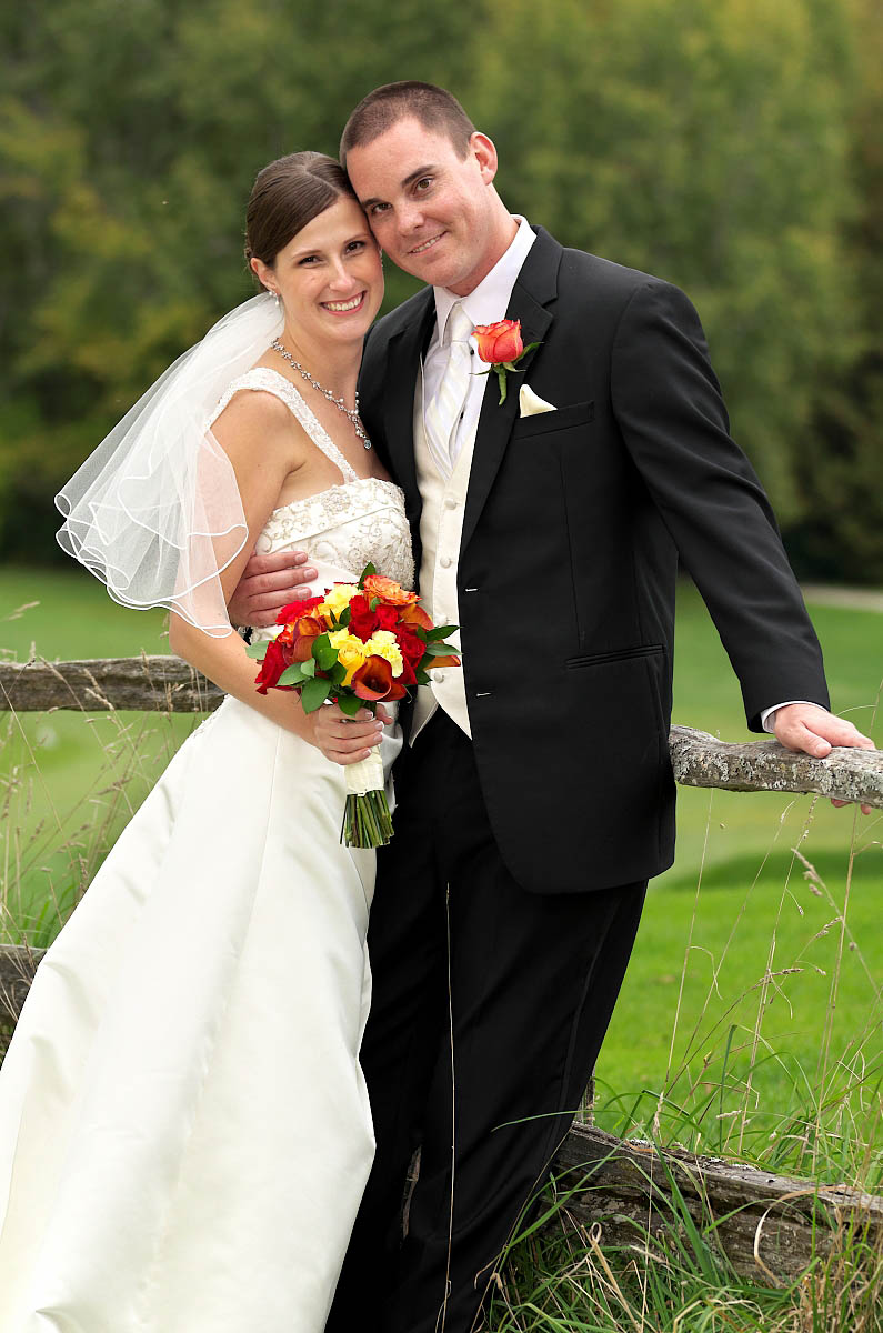 wedding couple by split rail fence at Eganridge Golf Club wedding