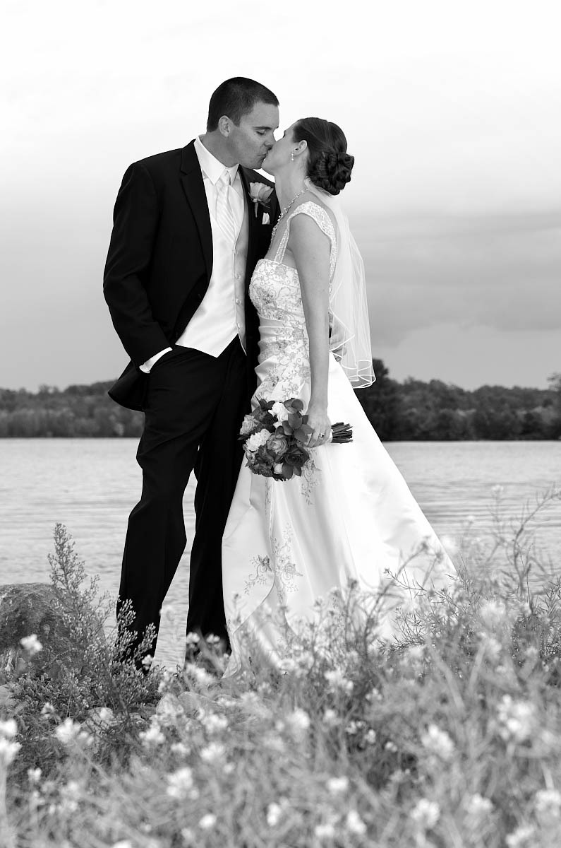 Bride and groom with wildflowers and lake at Eganridge wedding