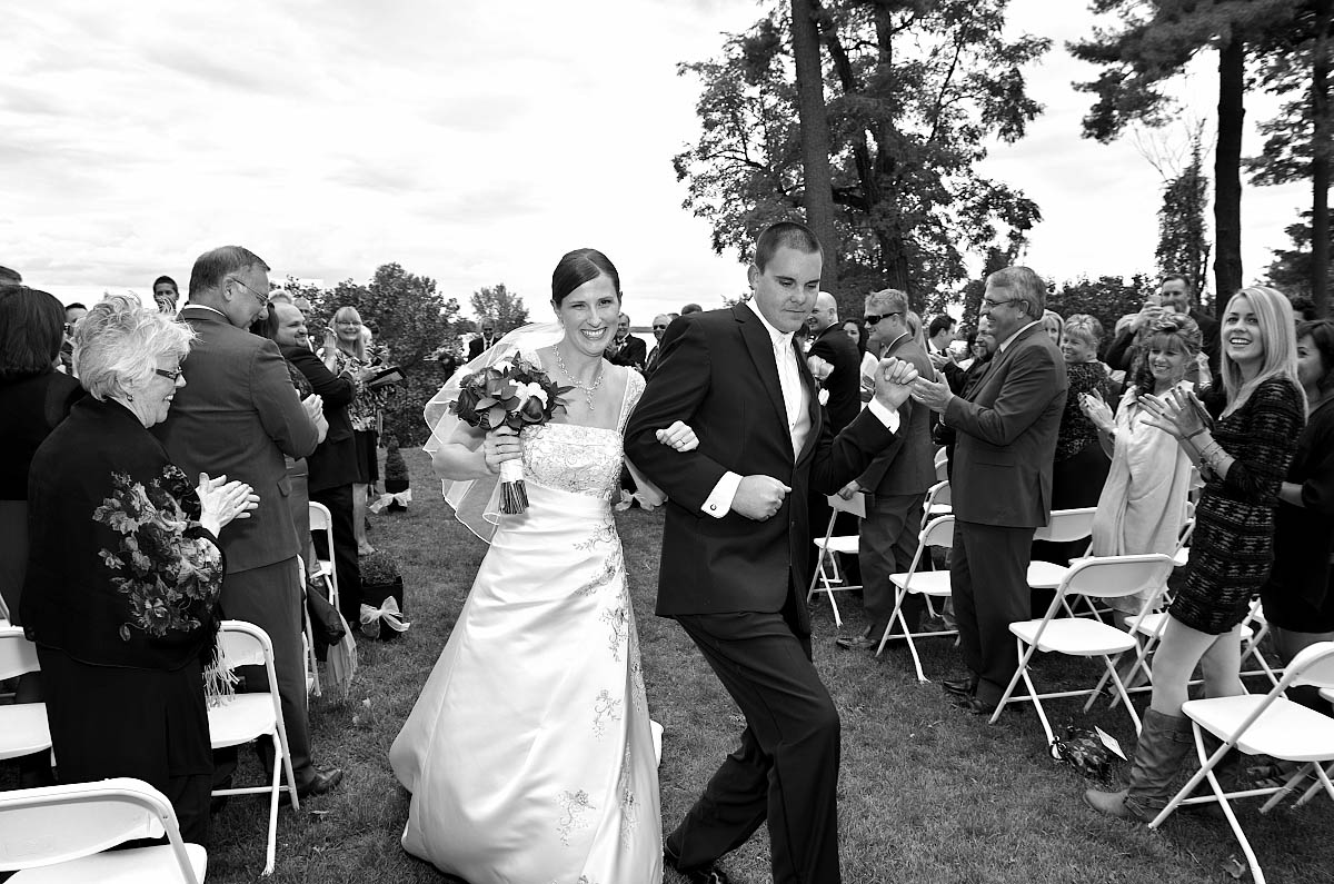Dynamic groom and bride walk together down ceremony aisle as husband and wife at Eganridge wedding