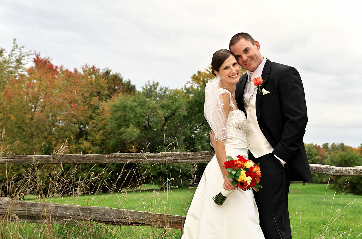wedding couple by split rail fence at Eganridge Golf Club wedding