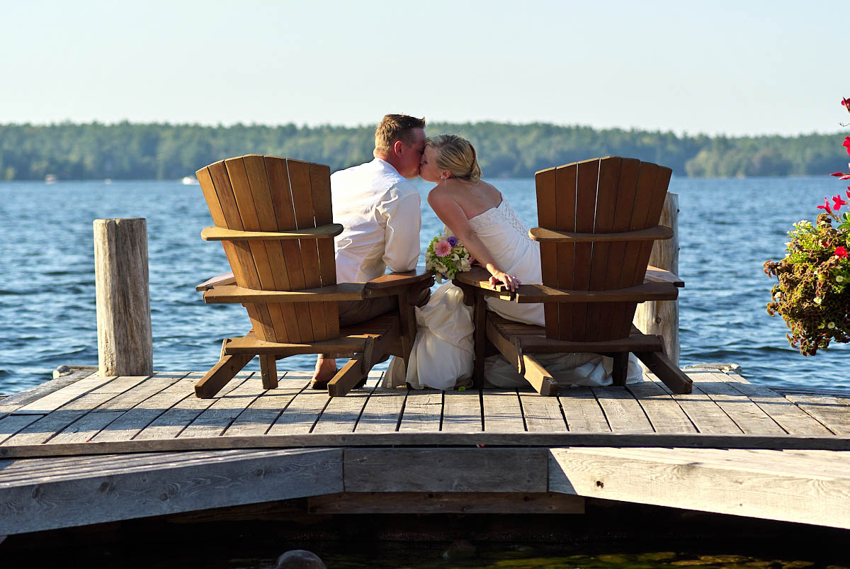 wedding couple kisses in muskoka chairs kissing at stoney lake wedding at irwin inn
