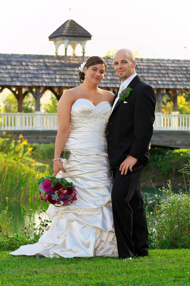 wedding couple in front of covered bridge
