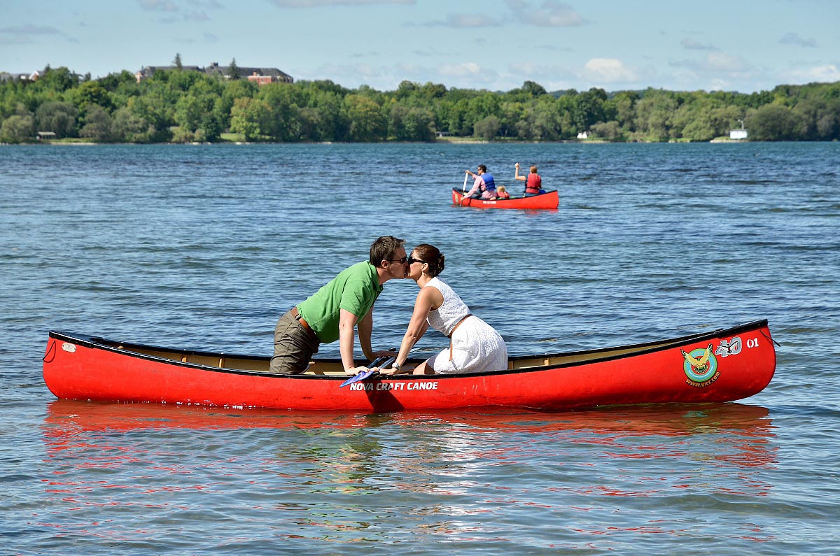 bride and groom kissing in red canoe at summer camp wedding