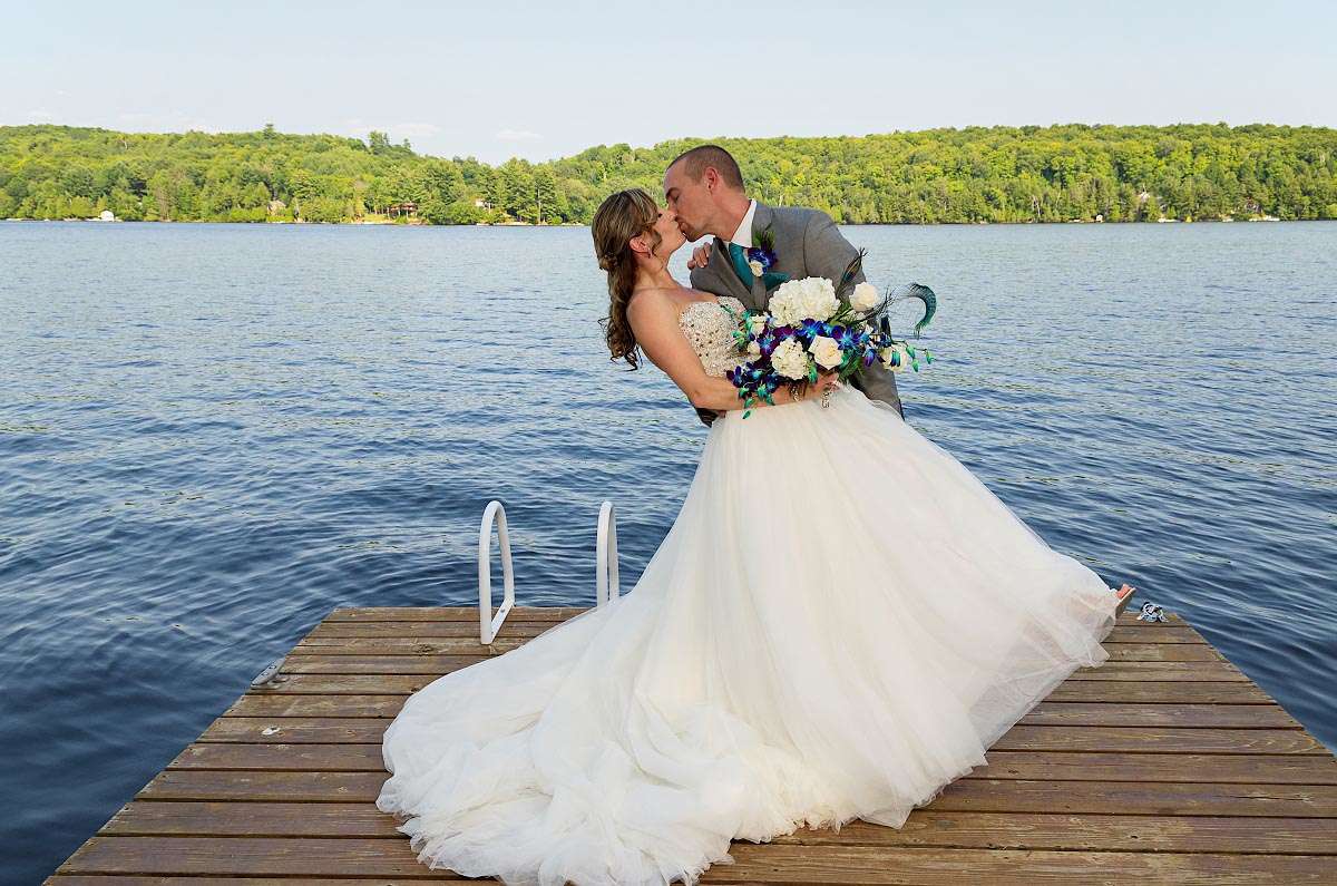 Groom passionately kisses and dips bride on dock at Haliburton wedding