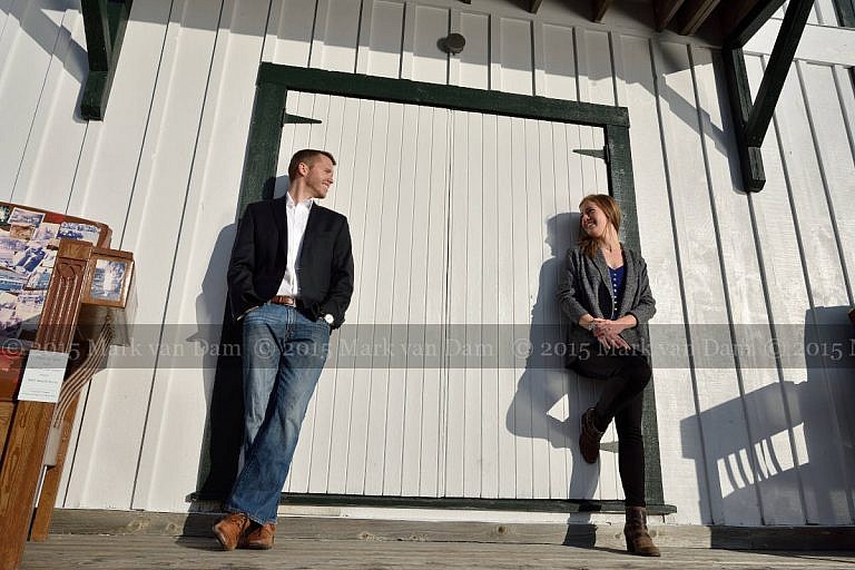 Stylish couple leans against boathouse door at Leacock Museum engagement photography session