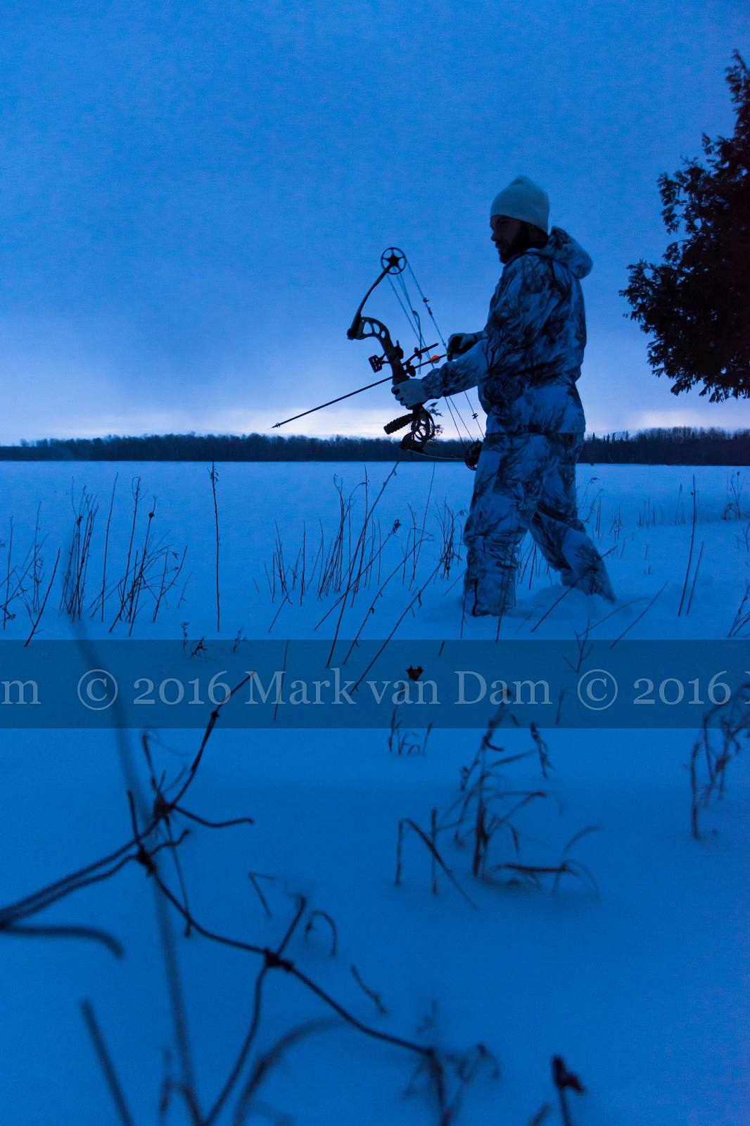 twilight silhouette of compound bow hunter in winter