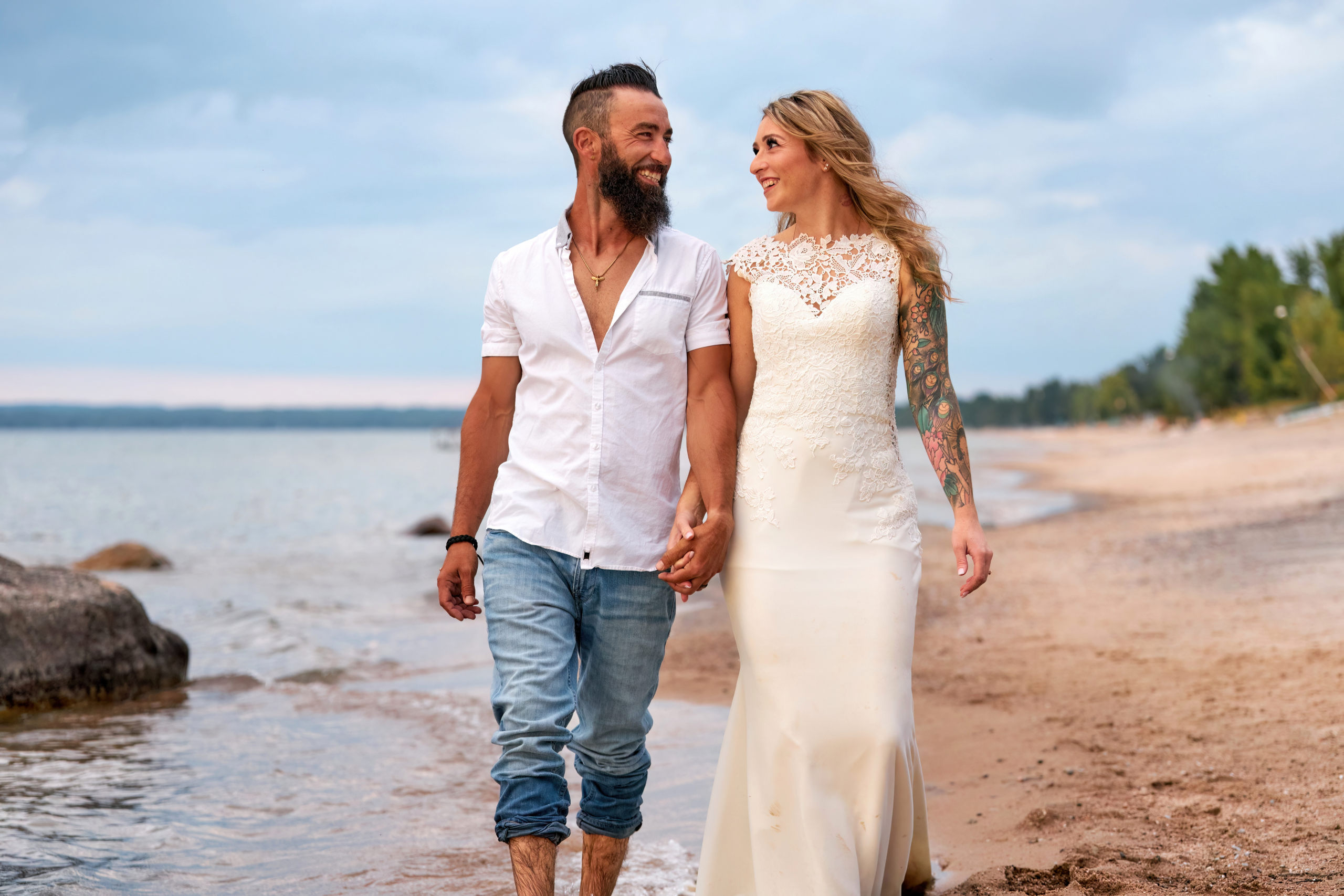 Happy Couple Walks Hand in Hand down Beach on Georgian Bay at Trash the Dress Session