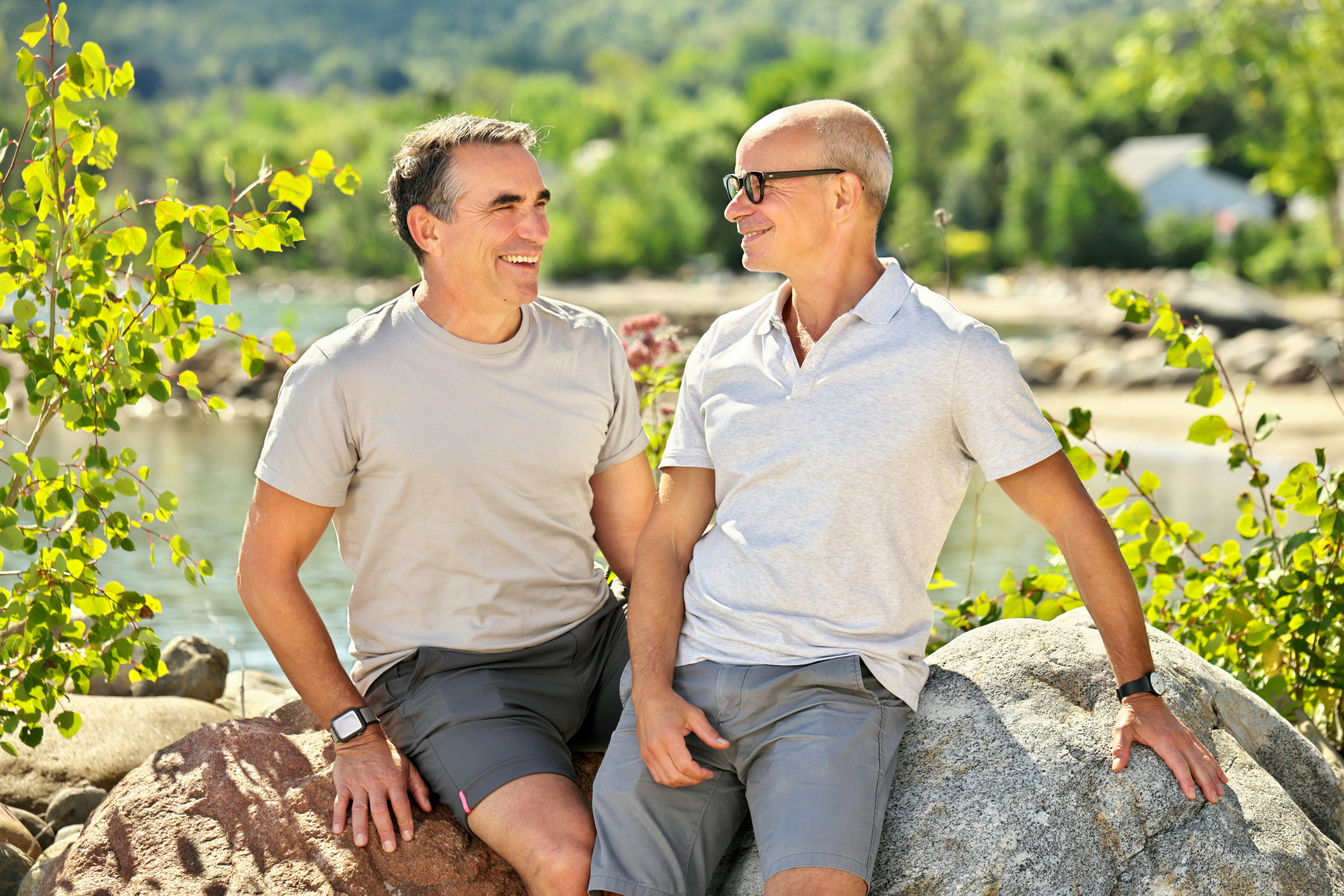 A couple looks tenderly at each other while sitting on boulders at beach in Craigleith