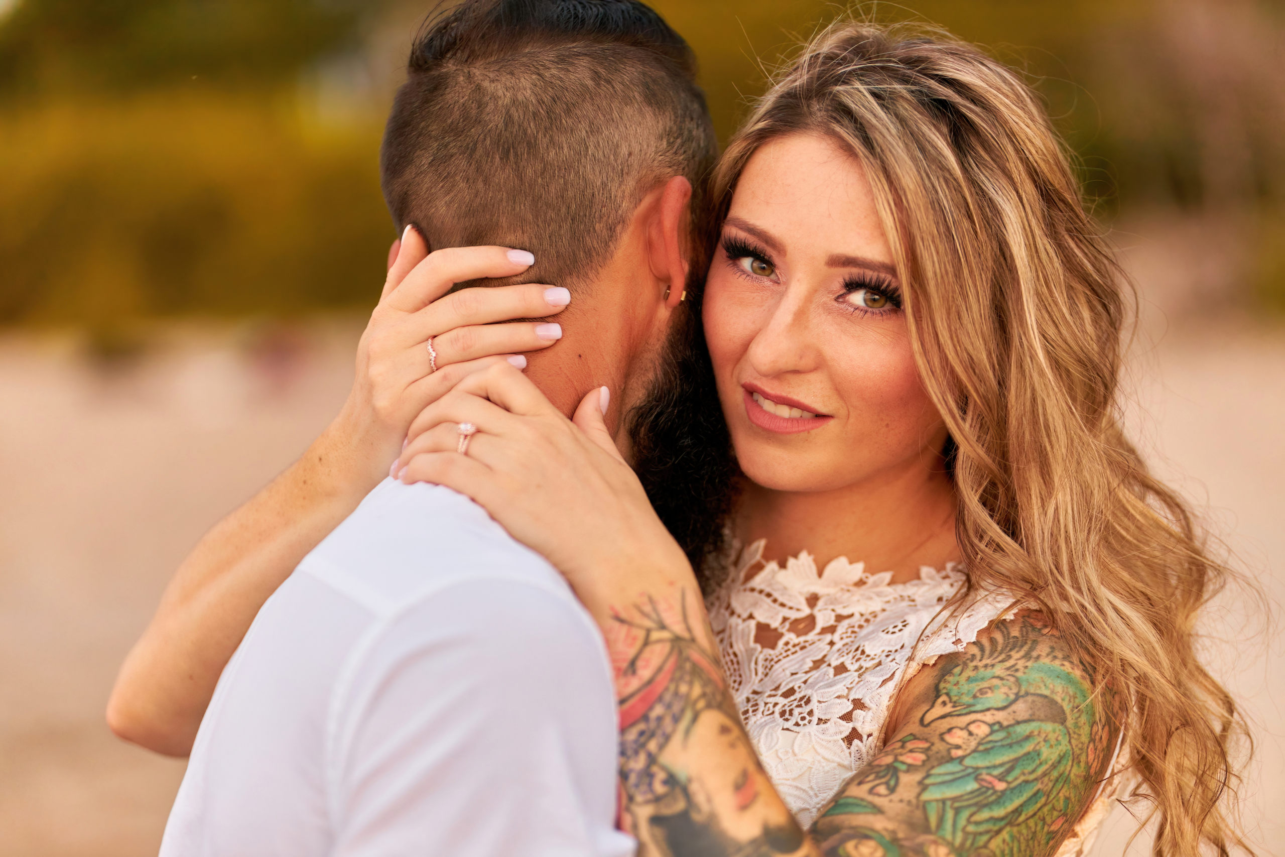 Close up of Woman pulling her Husband Close on Beach, looking over his shoulder