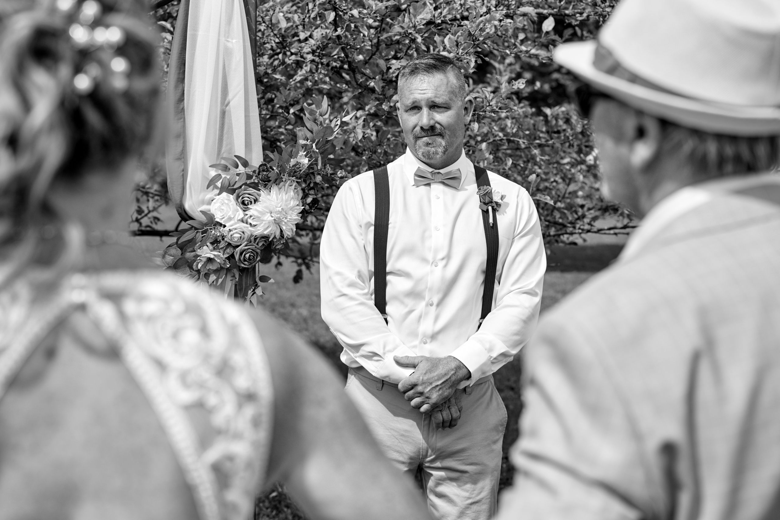 An emotional Groom watches his Wife approach at outdoor Wedding Ceremony